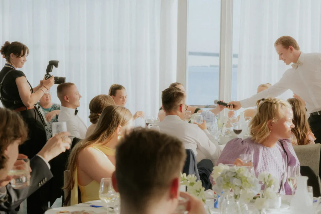 Hääjuhlan vieraat pöydissä valoisassa juhlasalissa