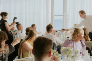 Hääjuhlan vieraat pöydissä valoisassa juhlasalissa